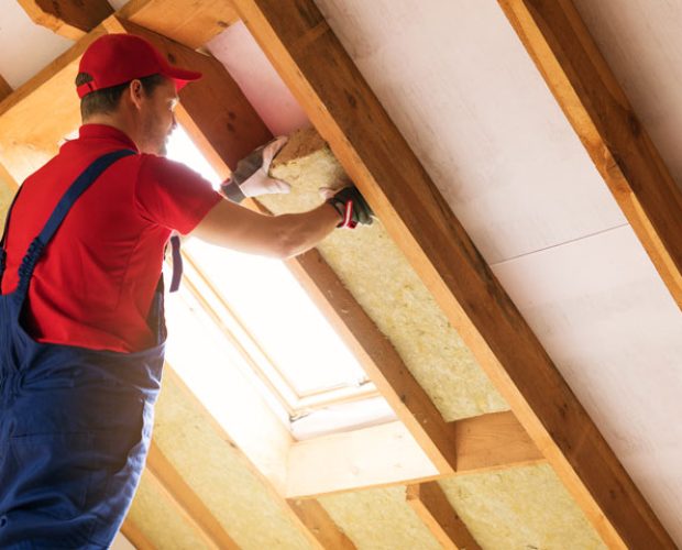 A skilled worker installing fiberglass for Attic Insulation