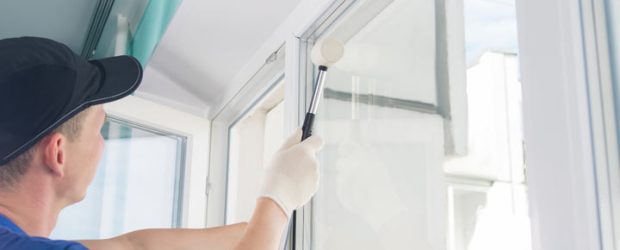 Window installation worker inserting glass into the frame and uses a rubber mallet to fasten the window