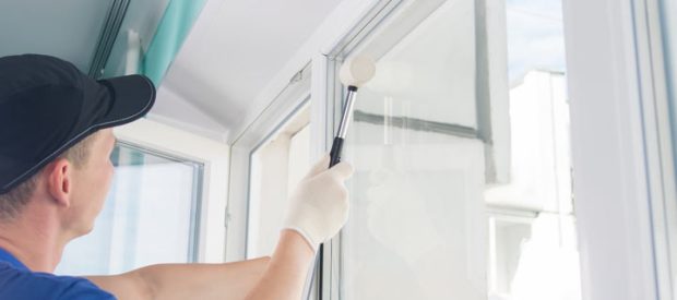 Window installation worker inserting glass into the frame and uses a rubber mallet to fasten the window